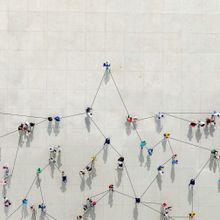 aerial photograph of several people standing on concrete with strings attaching them to represent social networks