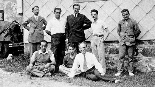 Black and white historical photo of eight men in front of a building, including Henri Cartan, André Weil and Szolem Mandelbrojt.