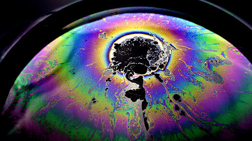 Close-up photograph of a soap bubble with a spot on it that looks as though it must have come from a collision.