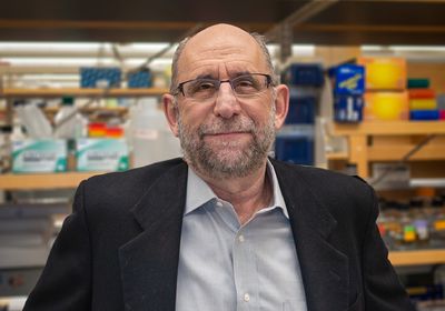Michael Green smiling at the camera in front of a shelf in the lab