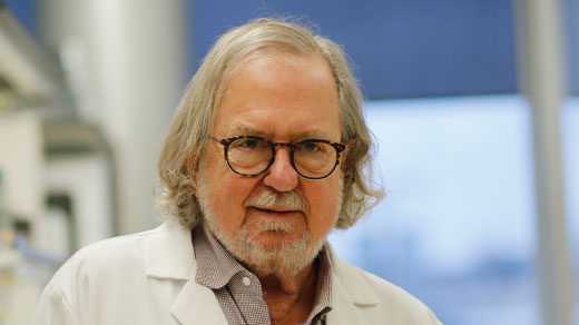 Photo of James P. Allison sitting at his desk at the MD Anderson Cancer Center.