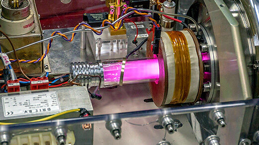 A pink beam at the center of a metallic experimental apparatus.