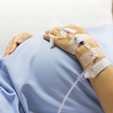 pregnant belly clad in hospital gown with IV line going into hand