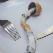 A psychedelic mushroom on a plate with a fork and knife