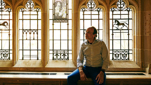 Daniel Spielman sits in front of an elaborate window at Yale University