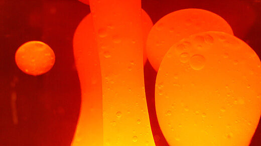 Close-up video of bubbles in a lava lamp moving and splitting under the influence of heat.
