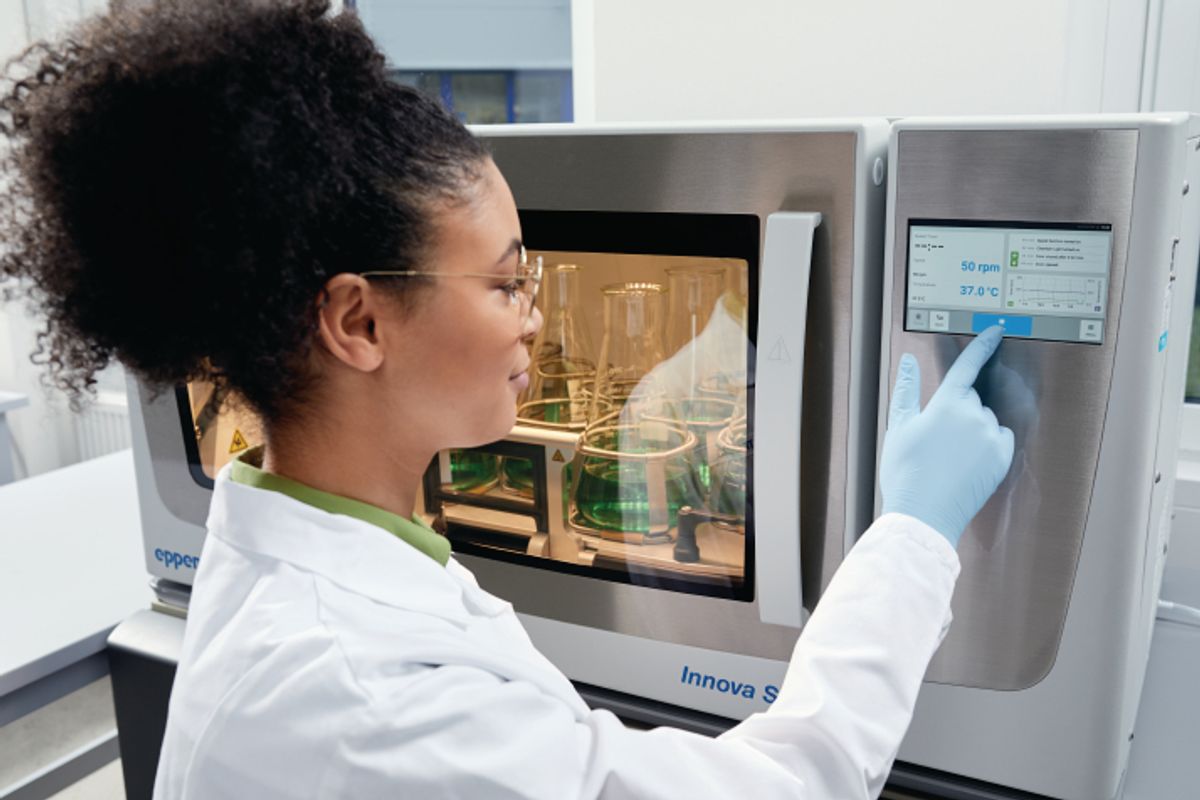 Woman in labcoat and gloves pushing a button on the Eppendorf VisioNize system